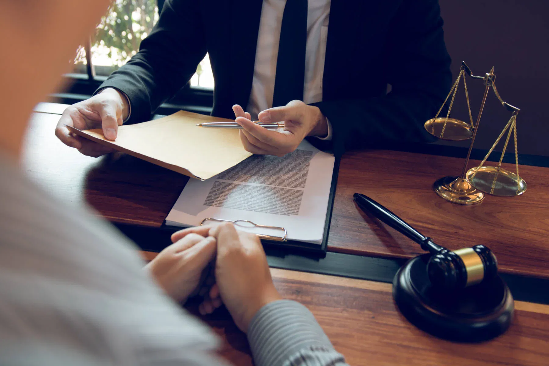 Steuerstrafrecht Anwalt berät Mandanten am Schreibtisch, mit Aktenmappe, Dokumenten, Waage und Richterhammer im Büro