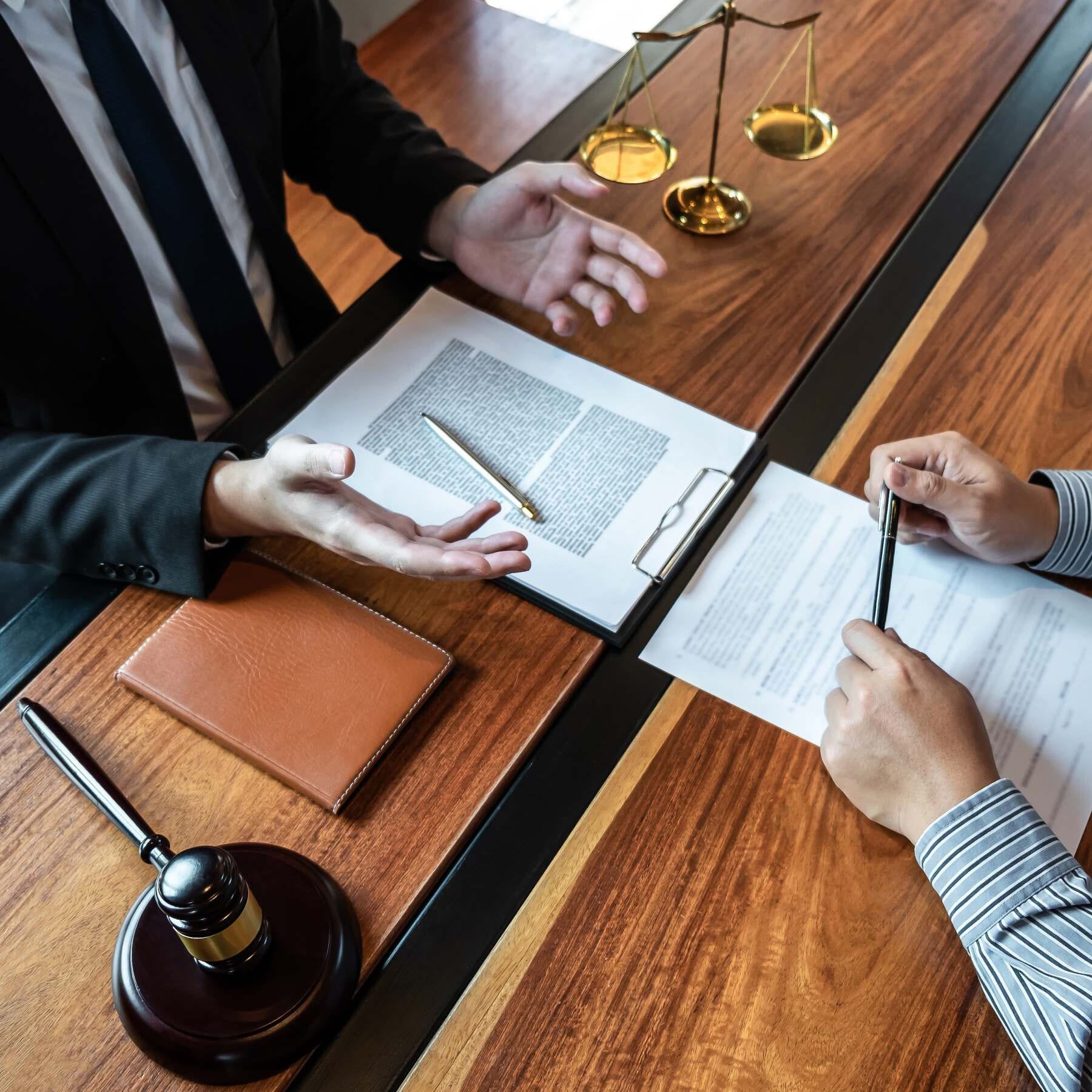 Steuerstrafrecht Anwalt berät Mandanten am Schreibtisch, Akten und Waage im Hintergrund