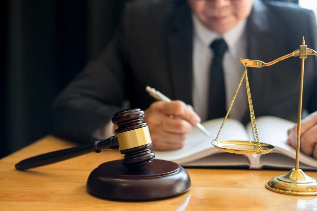 Steuerstrafrecht Anwalt berät zu Steuerverfahren; Richterhammer und Waage auf dem Schreibtisch im Hintergrund ein Jurist