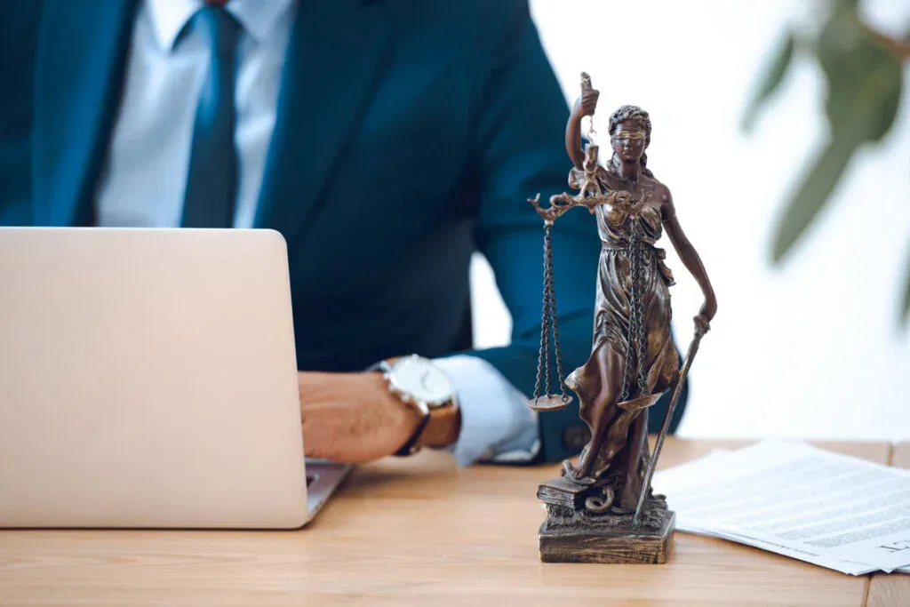 Justitia-Figur neben Laptop im Büro, Symbol für Online-Beratung beim Anwalt für Steuerstrafrecht